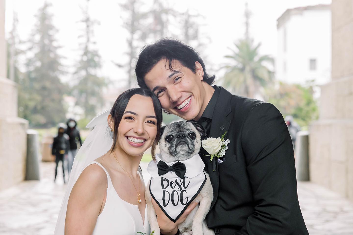 Aaron Burriss and his wife, Veronica Merrell, holding their pet dog at their wedding
