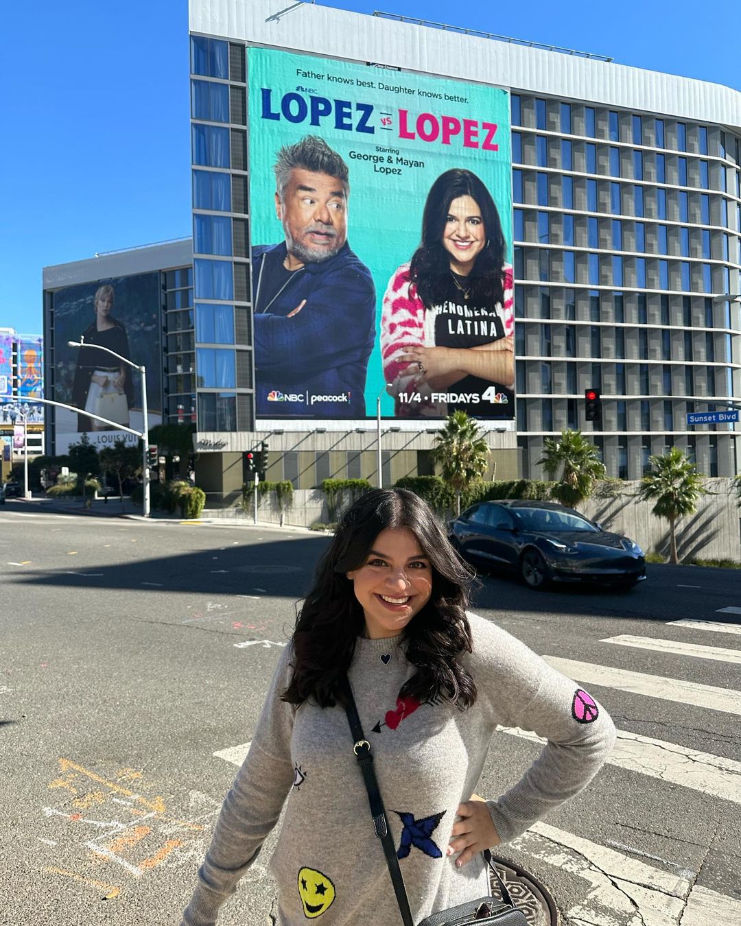 Mayan Lopez infront of 'Lopez vs. Lopez' billboard in West Hollywood
