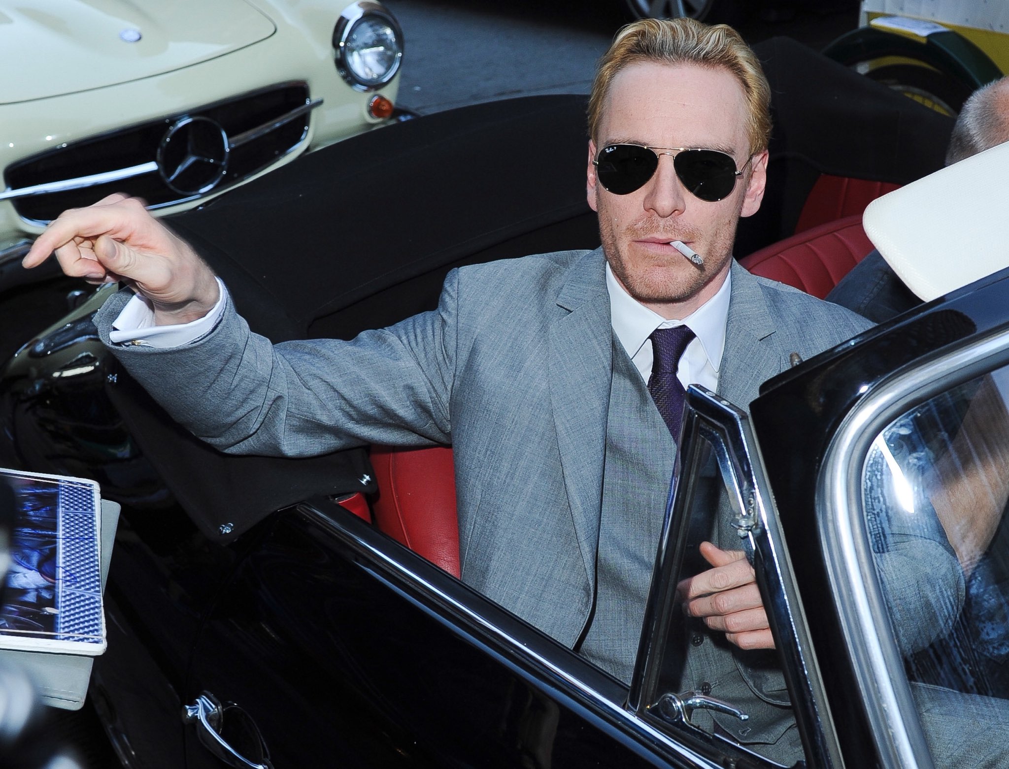 Michael Fassbender smoking a cigarette while riding a vintage car on his way to the premiere of ‘X-Men: First Class.’